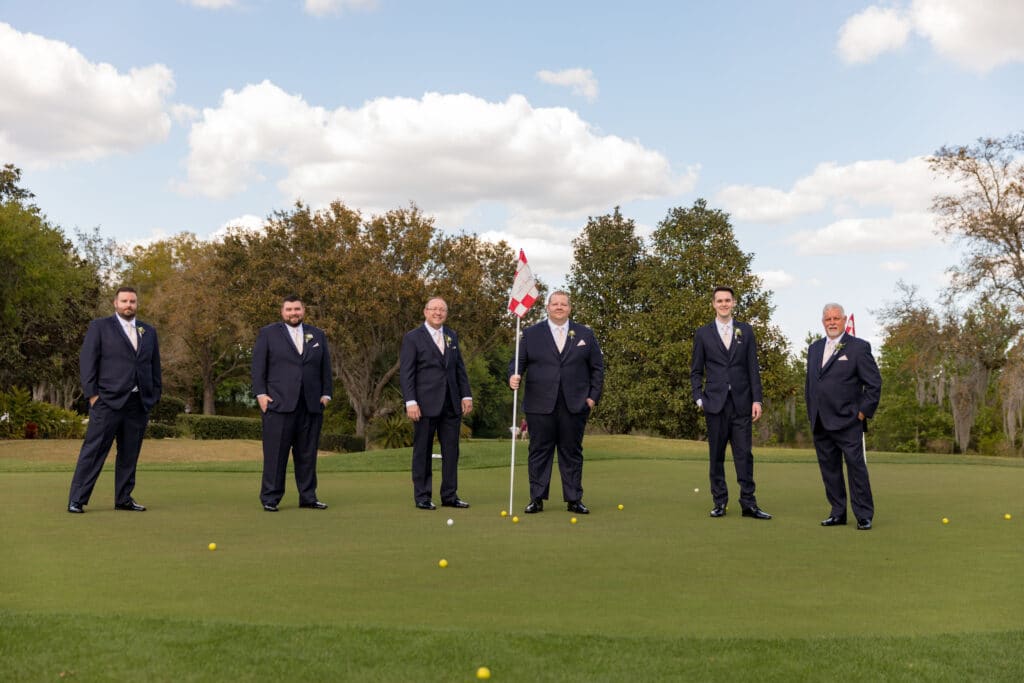 groom and his groomsmen standing on practice green at golf course